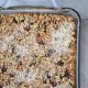 A pyrex baking dish full of delicious browned baked oatmeal spotted with orange carrot and raisins.