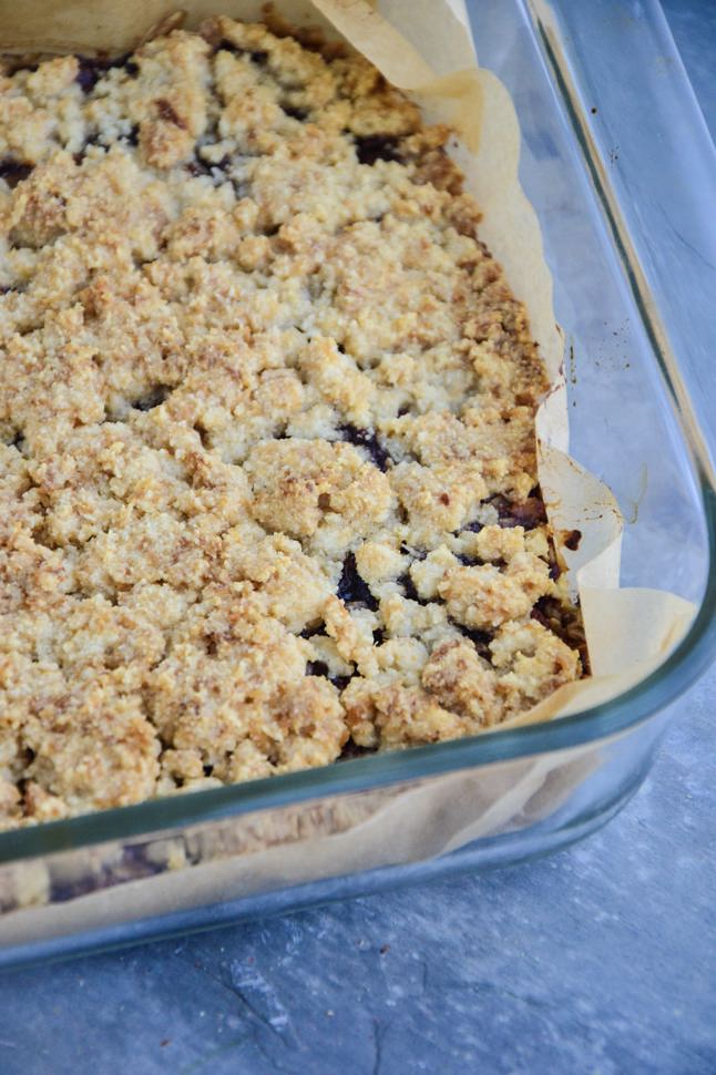 A close up of a baking dish filled with a crumbly cherry oat bar.